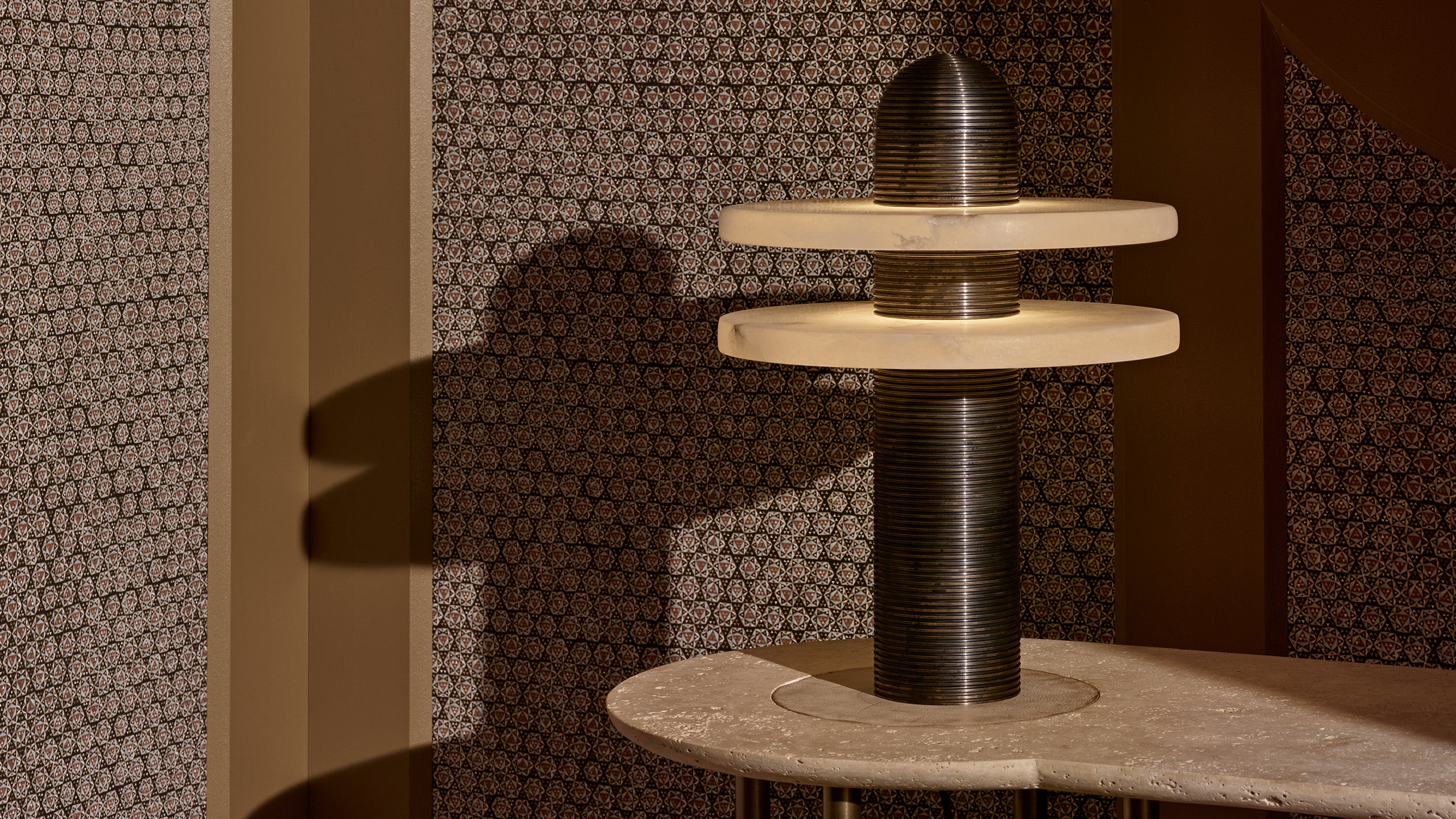 Artistic modern sculpture on a stone surface casting a shadow against patterned brown walls