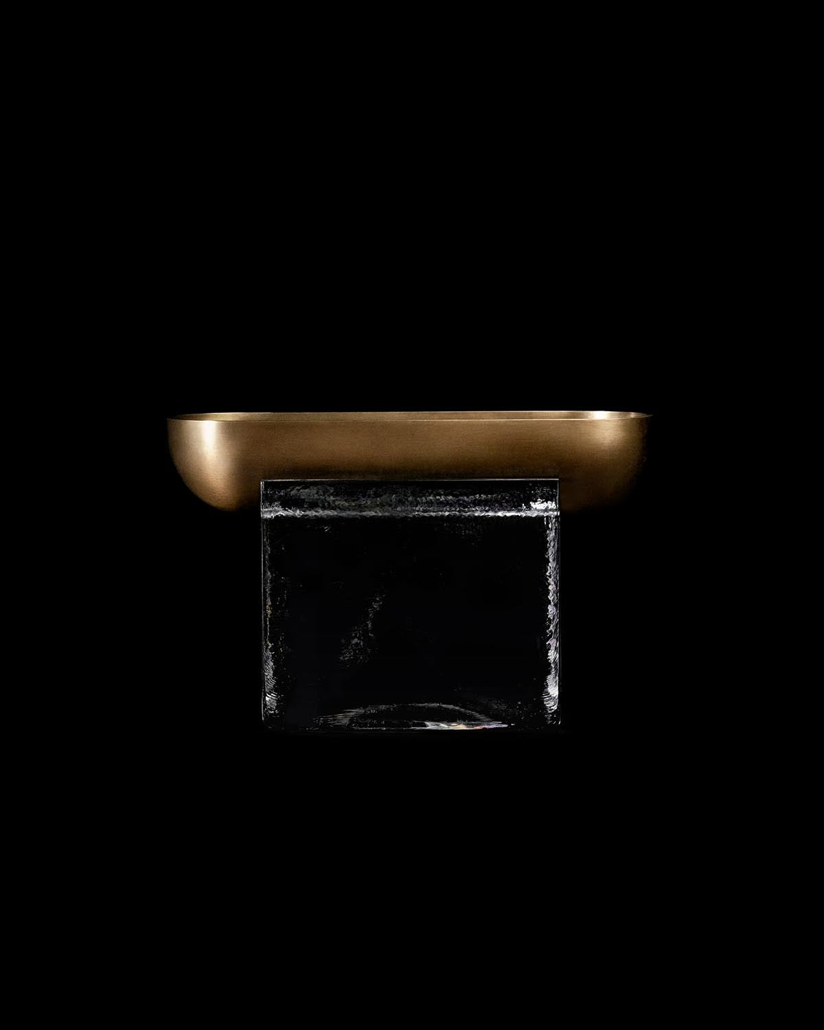Side view of a rectangular metallic vessel with smooth curved edges resting on a transparent rectangular base against black background