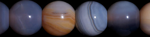 Close-up of translucent round beads with layered gray, white, and brown patterns on a black background