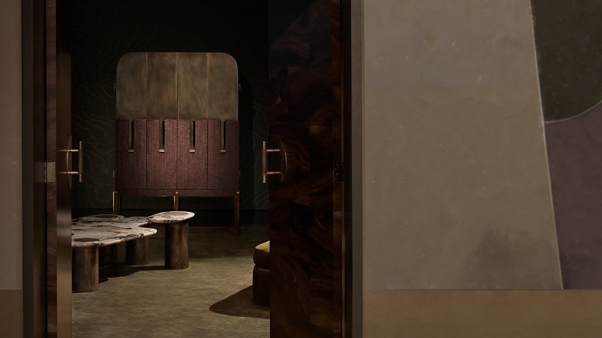Dimly lit interior scene showing a textured wooden door partially open to a room with a stone table and upholstered chair