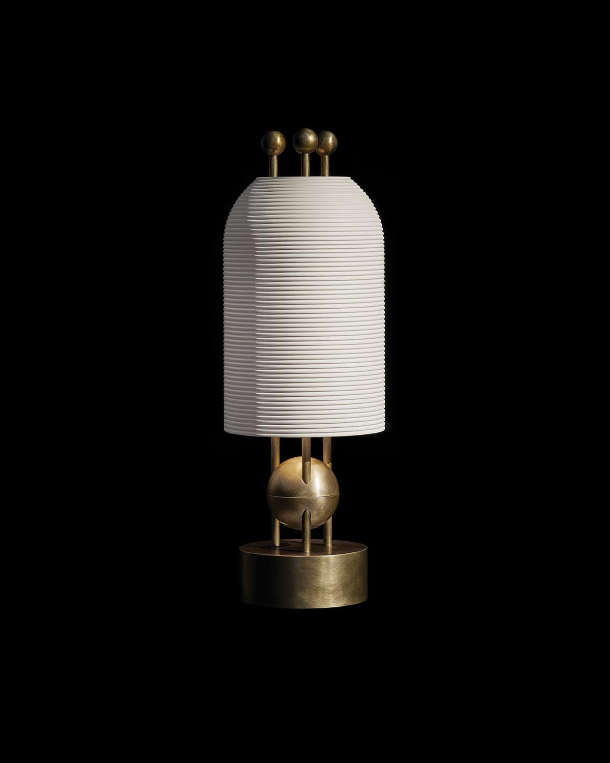 Modern table lamp with ribbed white cylindrical shade and brass geometric base on black background