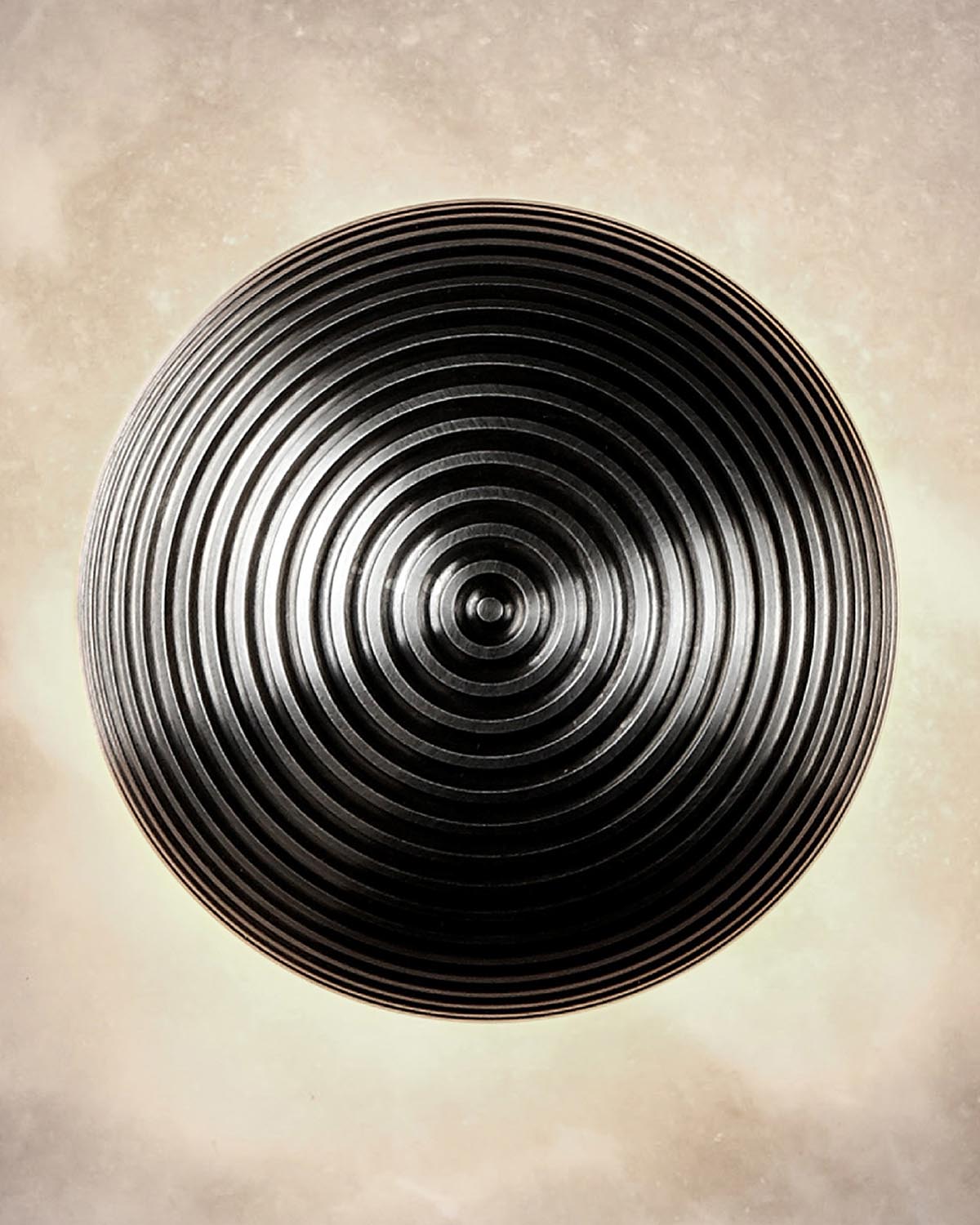 Top-down view of a circular black surface with concentric ridges creating a textured pattern on a light background
