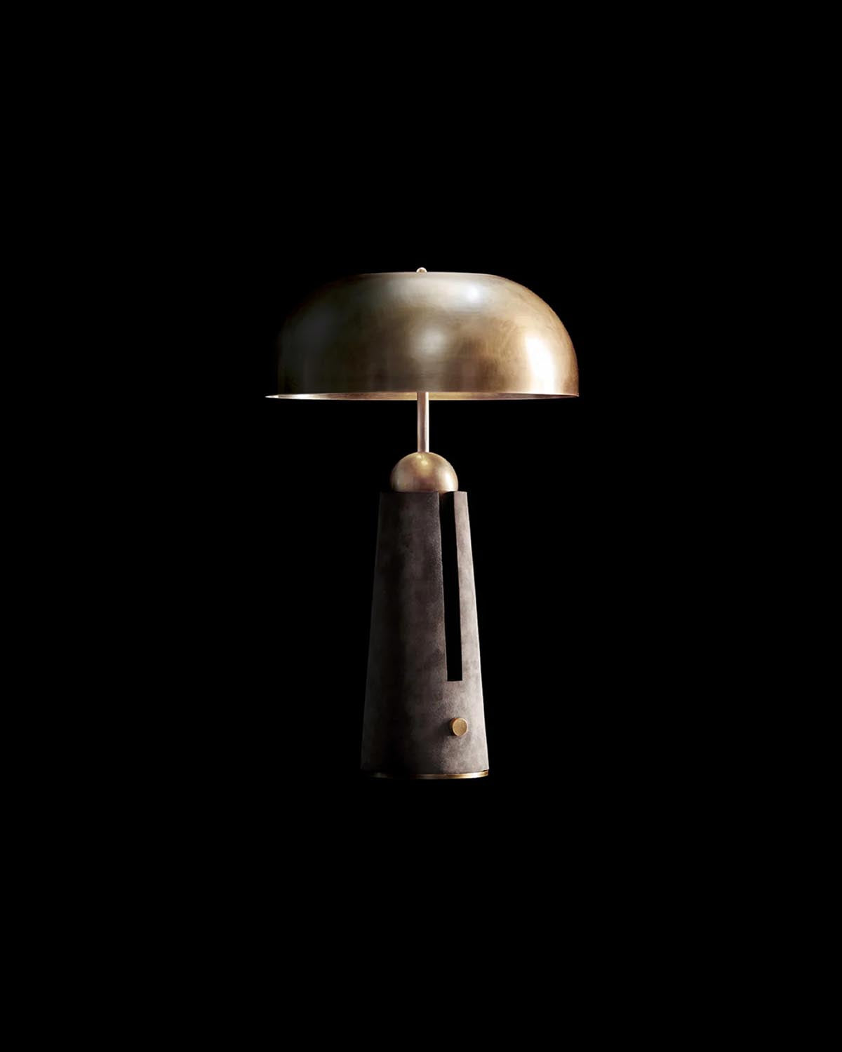 Minimalist table lamp with a dome-shaped metallic shade and geometric dark base against a black background