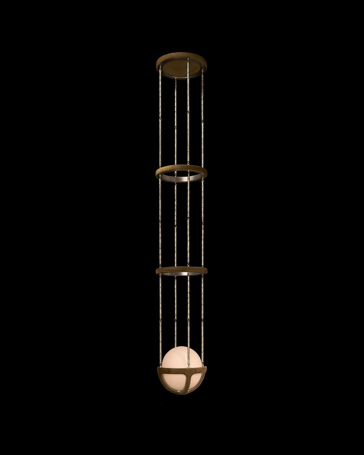 Vertical pendant light with three circular bronze frames and a glowing white orb suspended at the bottom against black background