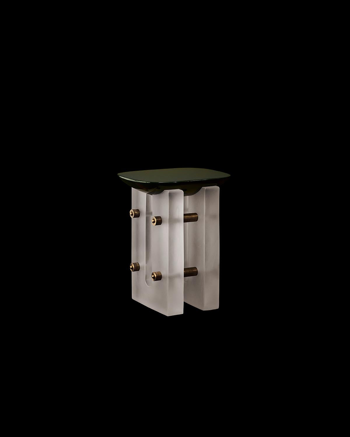 Cocktail table with a dark smooth top supported by frosted glass legs connected by brass rods on black background
